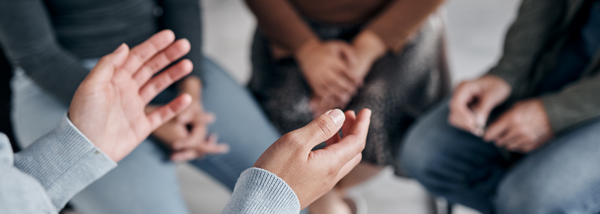 A close-up of a person's hands gesturing while speaking in a support group or therapy session.
