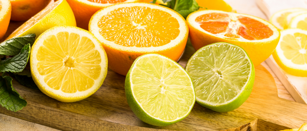 A close-up of freshly sliced citrus fruits, including lemons, limes, oranges, and grapefruits, arranged on a wooden cutting board.