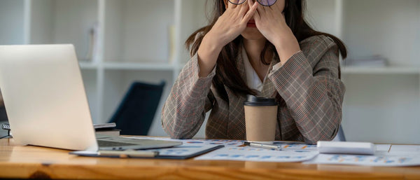 woman holding head in her hands at work desk