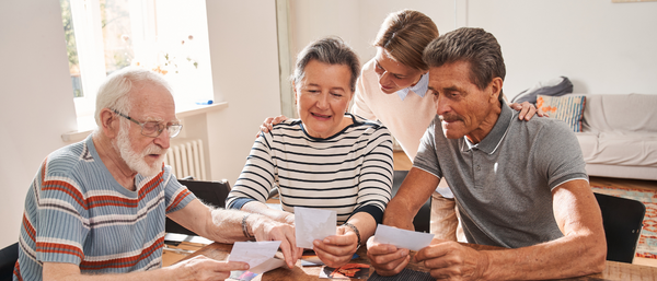 Elderly group reminiscing over photos with a younger woman.